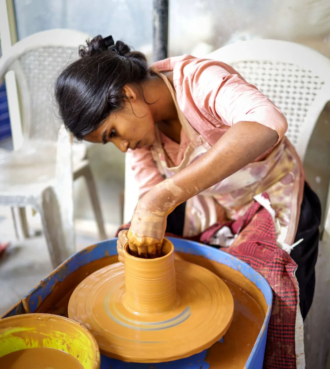 A young woman shapes a clay pot on the pottery wheel at the Headstreams studio